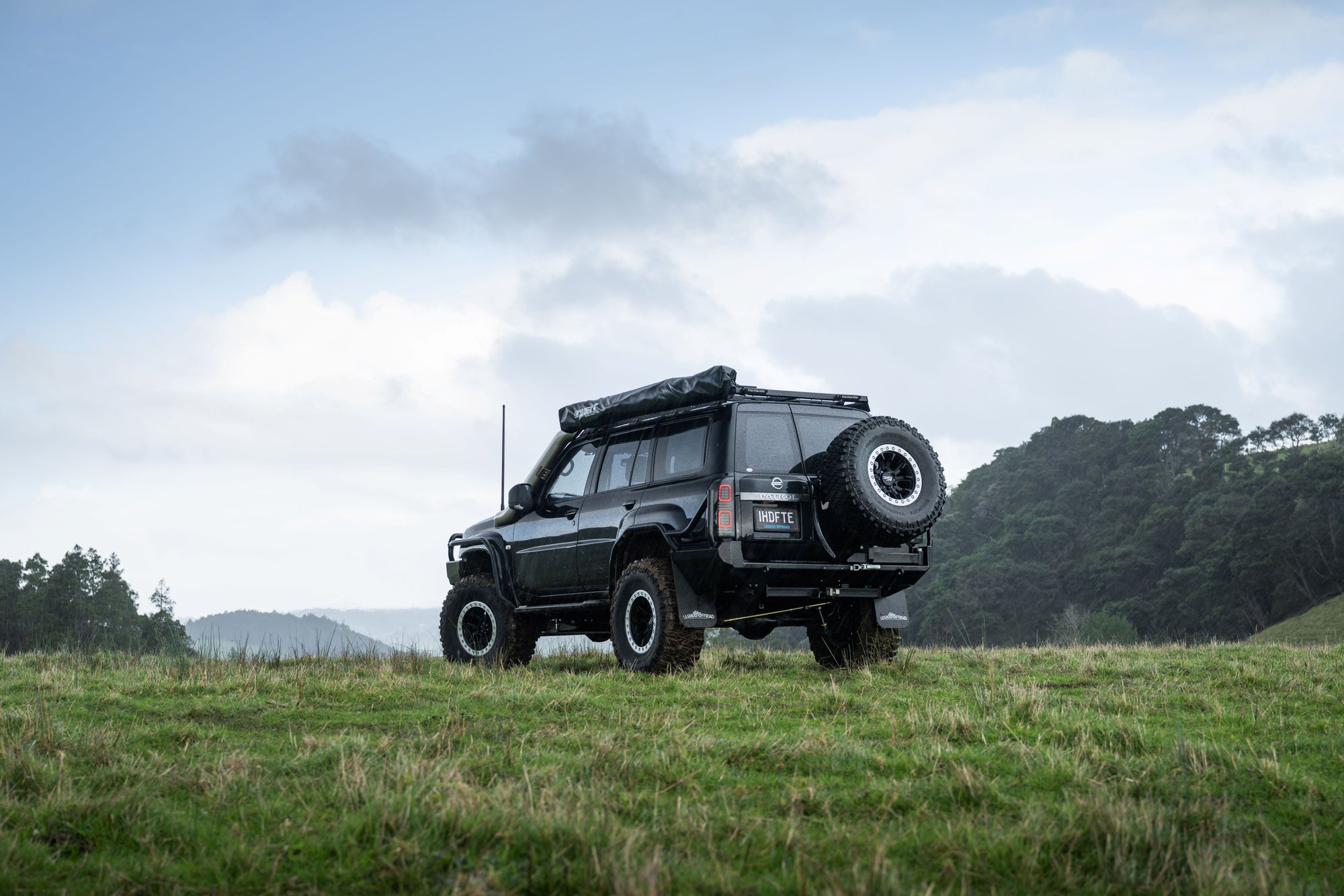 Modified Nissan Patrol touring vehicle fitted with off-road accessories, roof rack and mud terrain tyres photographed in rural New Zealand terrain by Off-Road Garage NZ